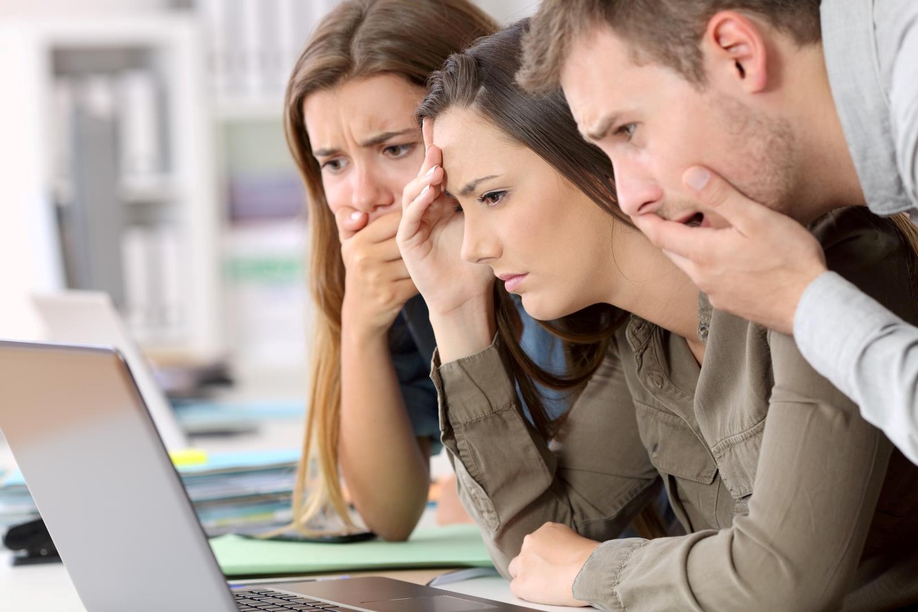 Employees looking disappointed at a computer